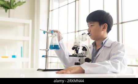 Kinderwissenschaftler lernen Biologie und Chemie im Labor. Ein MINT-Lernkonzept. Ein asiatischer Schülerjunge mit Mikroskop in A Stockfoto