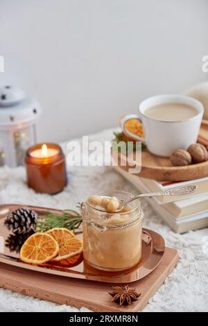 Ästhetisches Weihnachtsfrühstück. Hausgemachter, mit Nüssen gesalzener Karamell-Aufstrich im Glas mit einer Tasse Kaffee zu Hause. Stockfoto