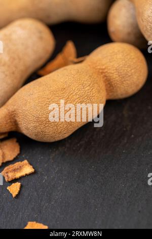 Geschlossene, lange reife Tamarindenschoten aus der Nähe, verzehrfertige ganze Tamarindenfrüchte liegen auf dem Tisch Stockfoto