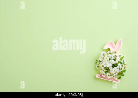 Frohe Ostern. Keramik rosa Form des Osterhasen mit runden Bouquet Quellen frische Kirsch- oder Apfelblüten auf grünem Hintergrund. Osterkarte für den Frühling Stockfoto