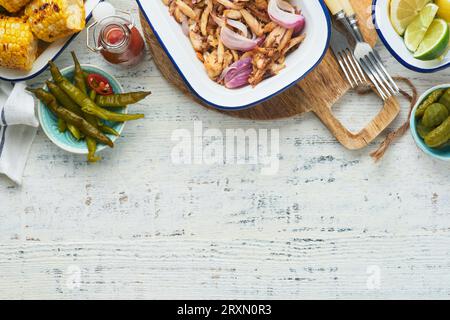 Gezapftes bbq-Hühnchen mit gebackenen Zwiebeln auf Servierplatte, bbq-Mais, Gurken, Chilischoten und Brötchen für Hot Dogs und Burger, Tomatensauce. Traditionell Stockfoto