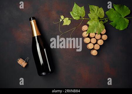 Flasche Champagner, Traubenstrauß Kork mit Blättern auf rostigem Hintergrund, Draufsicht Stockfoto