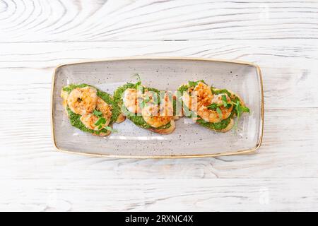 Bruschetta mit Garnelen auf Ciabatta-Toast mit Avocadocreme und Pesto-Sauce. Hochwertige Fotos Stockfoto