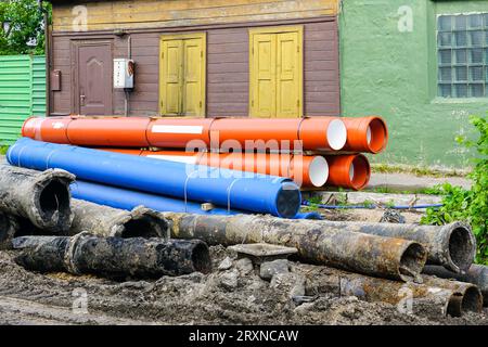 Austausch der unterirdischen Wasserversorgung und Abwasserleitungen in der Stadtstraße, schmutzige alte Rohre neben neuem blauen Plastikwasser und braunen Abwasserleitungen Stockfoto