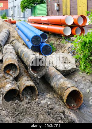 Austausch der unterirdischen Wasserversorgung und Abwasserleitungen in der Stadtstraße, schmutzige alte Rohre neben neuem blauen Plastikwasser und braunen Abwasserleitungen Stockfoto