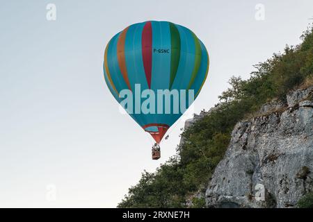 Rocamadour, Frankreich - 24. September 2023: Ein Heißluftballon scheint gefährlich nahe einer Klippe und Zuschauer während der Montgolfiades zu passieren Stockfoto