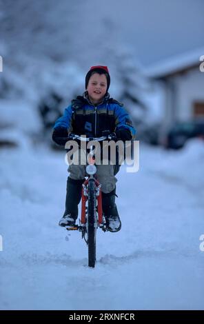 Kleiner Junge auf dem Bauernhof Fahrrad, im Winter reiten, Schnee 8 9 10 11 Jahre alt Stockfoto