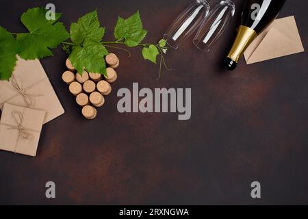 Flasche Champagner, ein Büschel Kork mit Blättern, zwei Weingläser und Umschlag auf rostigem Hintergrund, Draufsicht. Stockfoto