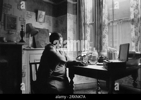 Ältere Dame saß im vorderen Raum ihres viktorianischen Hauses, das auf den Abriss während der Räumung des Slums von St Ann's, Nottingham, England, wartet. Stockfoto