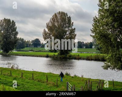 Nijmegen, Niederlande. September 2023. Eine Frau sah neben dem Fluss spazieren. Mit der Ankunft im Herbst an diesem Wochenende können die Menschen warme Temperaturen auf dem Land genießen, indem sie mit dem Fahrrad fahren oder entlang der Deiche und Wälder wandern. Auch landwirtschaftliche Nutztiere genießen die Weide. (Foto: Ana Fernandez/SOPA Images/SIPA USA) Credit: SIPA USA/Alamy Live News Stockfoto