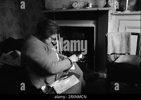 Ältere Dame saß im vorderen Raum ihres viktorianischen Hauses, das auf den Abriss während der Räumung des Slums von St Ann's, Nottingham, England, wartet. Stockfoto