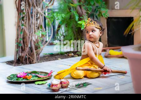 Entzückendes Kleinkind gekleidet als hindugott krishna niedlicher Gesichtsausdruck mit Flöte bei Janmashtami Stockfoto