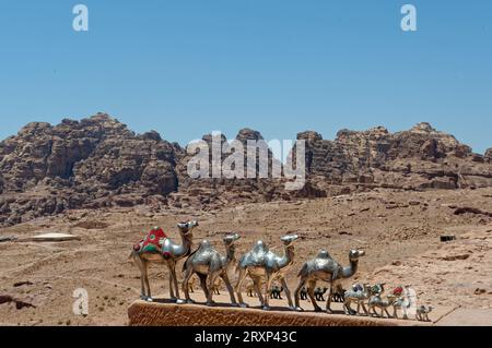 Metallkamele auf einer erhöhten Ebene mit den prächtigen Felsformationen von Petra im Hintergrund. Einzigartige Souvenirs von Jordanien. Stockfoto