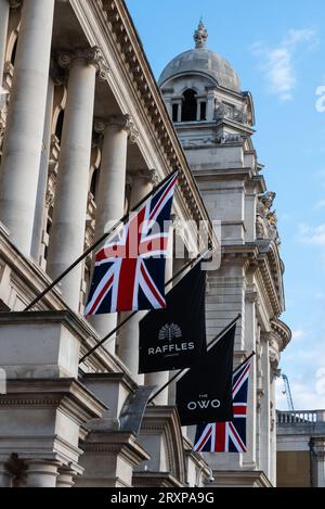 Raffles Hotel, das aus dem Gebäude des Old war Office in Whitehall, Westminster, London, Großbritannien, umgebaut wurde. Die OWO. Flaggen draußen Stockfoto