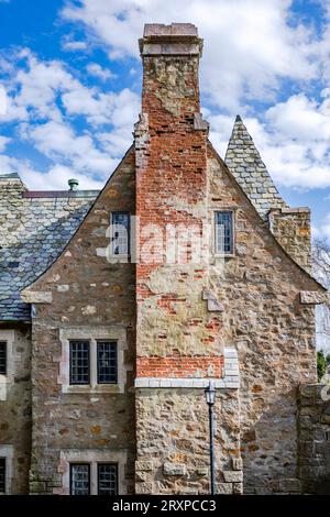 Ein altes, dreistöckiges Steinhaus mit rotem Backsteinkamin und einem spitzen Dach im skandinavischen Stil blickt mit kleinem Gitter auf die Welt Stockfoto