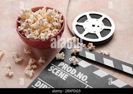 Schüssel mit leckerem Popcorn, Klappbrett und Folienrolle auf hellem Hintergrund Stockfoto