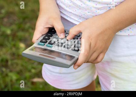 Anonymes junges Mädchen, das einen generischen Rechner benutzt, ihn in den Händen hält, zählt, grundlegende Mathematik macht, Mathematik lernt und moderne Bildung sim Stockfoto