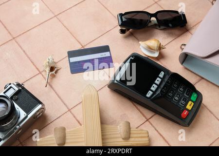 Komposition mit Zahlungsterminal, Kreditkarte und Sonnenbrille auf farbigem Kachelhintergrund Stockfoto