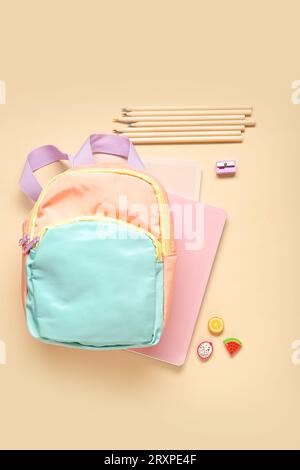 Stylischer Schulrucksack mit verschiedenen Schreibwaren auf orangefarbenem Hintergrund Stockfoto