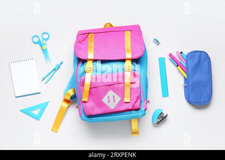 Stylischer Schulrucksack mit verschiedenen Schreibwaren auf grauem Hintergrund Stockfoto