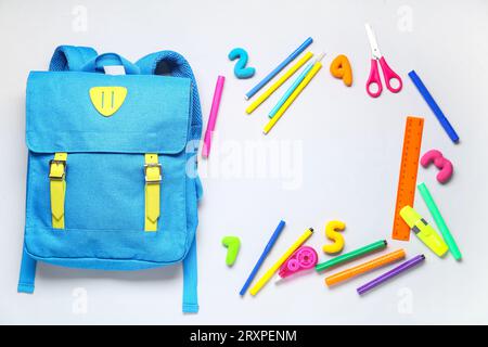 Stylischer Schulrucksack mit verschiedenen Schreibwaren auf grauem Hintergrund Stockfoto