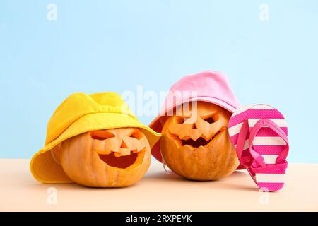 Geschnitzte Kürbisse für Halloween mit stylischen Hüten und Flip-Flops auf blauem Hintergrund Stockfoto