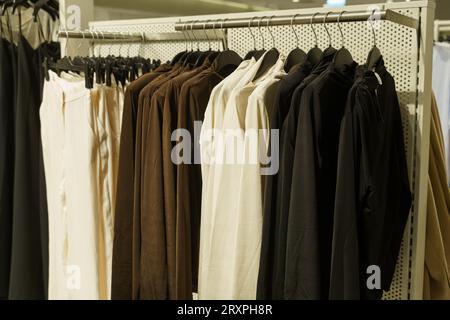 Moderne einfarbige Kleidung - Hosen und Pullover, auf einem Kleiderbügel im Laden. Stockfoto