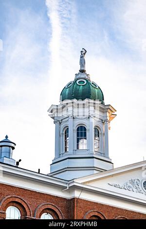 Ein klassisches, altes, mehrstöckiges Gebäude aus rotem Backstein in geometrischer Form mit Turm und der Statue von Themis mit Skalen in der Hand auf der Kuppel von Stockfoto