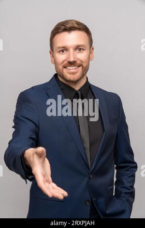 Ein lächelnder Geschäftsmann hält die Hand und bietet an, Geschäfte zu machen. Porträtmann, der die Handfläche zum Händewaschen auszieht Stockfoto