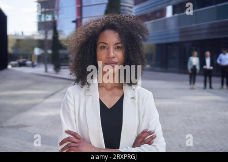Porträt einer seriösen afroamerikanischen Geschäftsfrau mittleren Alters, die Kameraarme überkreuzt betrachtet. Stockfoto