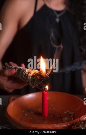 Ein Weihrauch anzünden, eine Hexe am Vorabend aller Heiligen, die ein Reinigungsritual durchführt, Halloween, spirituelle Überzeugungen, weiße Magie Stockfoto