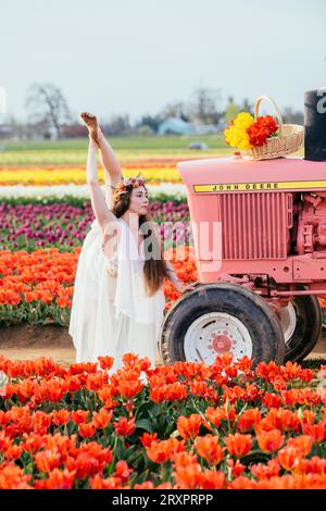 Frau, die einen bunten Regenschirm hält und sich auf dem rostigen Traktor teilt Stockfoto