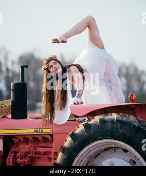 Frau, die einen bunten Regenschirm hält und sich auf dem rostigen Traktor teilt Stockfoto