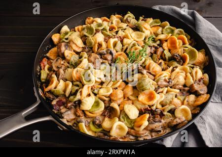 Orecchiette mit Pilz-Thymian-Sauce in einer Pfanne: Nudeln und Pilze in Sahnesauce, serviert in einer großen Bratpfanne Stockfoto