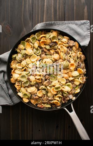 Orecchiette mit Pilz-Thymian-Sauce in einer Pfanne: Nudeln und Pilze in Sahnesauce, serviert in einer großen Bratpfanne Stockfoto