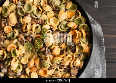 Orecchiette mit Pilz-Thymian-Sauce in einer Pfanne: Nudeln und Pilze in Sahnesauce, serviert in einer großen Bratpfanne Stockfoto