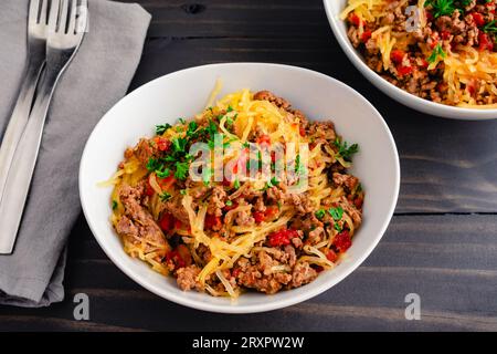 Spaghetti-Kürbis Bolognese garniert mit Petersilie: Schüsseln mit Spaghetti-Kürbis, serviert mit gemahlenem Rindfleisch und Tomatensauce Stockfoto