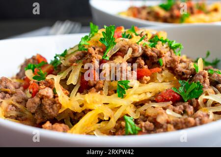 Spaghetti-Kürbis Bolognese garniert mit Petersilie aus nächster Nähe: Schüssel mit Spaghetti-Kürbis serviert mit gemahlenem Rindfleisch und Tomatensauce Stockfoto