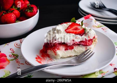 Erdbeercreme-Torte mit Schlagsahne: Ein Stück Erdbeertorte auf einem kleinen Teller mit einem Happen Stockfoto