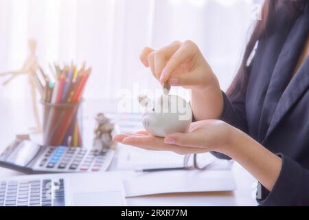 Münzen auf der Hand abgeworfen werden Sparschwein auf hölzernen Tisch, Geld zu sparen, Konzept Stockfoto