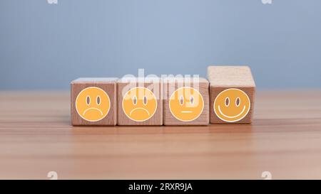 Psychische Gesundheit und emotionaler Zustand Konzept, Lächeln Gesicht und trauriges Gesicht auf Holzblock Würfel für positive Mentalität Selektionskonzept. Stockfoto