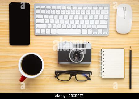Holzschreibtischbüro mit Laptop, Smartphone und anderen Arbeitsmaterialien mit einer Tasse Kaffee. Draufsicht mit Kopierraum für die Texteingabe. Arbeitsbereich des Konstrukteurs o Stockfoto