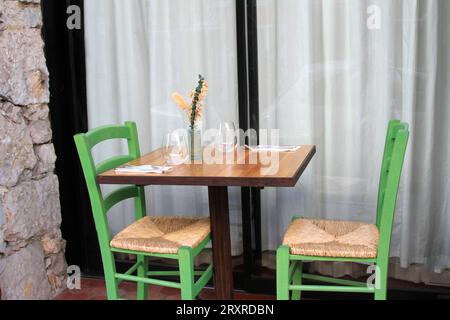 Tisch im Freien mit zwei grünen Stühlen und Rattansitzen Stockfoto