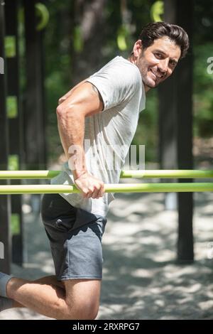 Muskulöser Mann, der an der horizontalen Stange im Park Pull-ups macht Stockfoto
