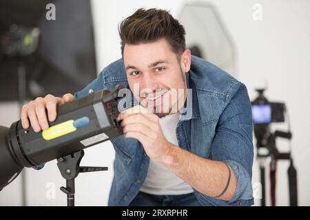 Der Fotograf passt das Blitzlicht im Studio an Stockfoto