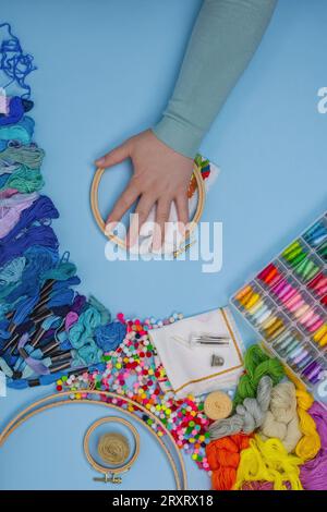 Stickerei auf Leinwand mit Frauenhänden. Frau stickt auf dem Tisch, wenn sie Zeit zur freien Verfügung hat. Stockfoto