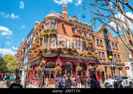 Ein mit Blumen verziertes rotes Ziegelgebäude an der Ecke der Neal Street und Shelton Street im Covent Garden. London, England Stockfoto