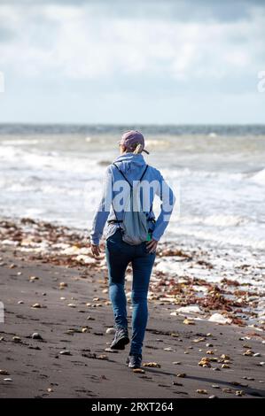Junge Frau, die in der Herbstsaison am einsamen Strand auf der isle of wight spaziert Stockfoto