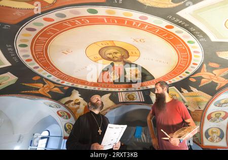 21. September 2023, Sachsen, Leipzig: In der neuen Rumänisch-Orthodoxen Kirche St. George’, der Priester Ioan Forga (l), spricht über die Malerei der Kirche mit dem Kirchenmaler Lektor Dr. Mihai Coman, Dozent für Kirchenmalerei an der Fakultät für Orthodoxe Theologie der Universität Bukarest. Nach einer in Deutschland selten verwendeten Technik werden derzeit die ersten Fresken auf das Gewölbedach der Kirche aufgebracht. Nach einer Maltechnik, die ihren Ursprung in der Antike hat, müssen bis zu sieben Schichten Kalksand aufgetragen werden, was, gemischt mit Rosshaar oder Hanffilz, garantieren sollte Stockfoto