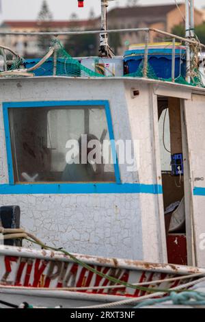 griechischer Fischer, der allein im Rollhaus eines alten Holzfischbootes auf der griechischen Insel zante oder zakynthos sitzt Stockfoto